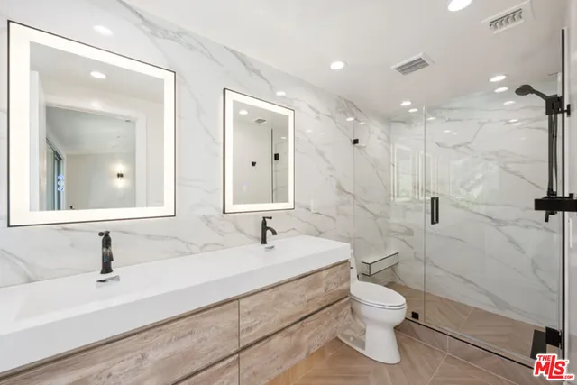 a bathroom with a sink a toilet and a large mirror