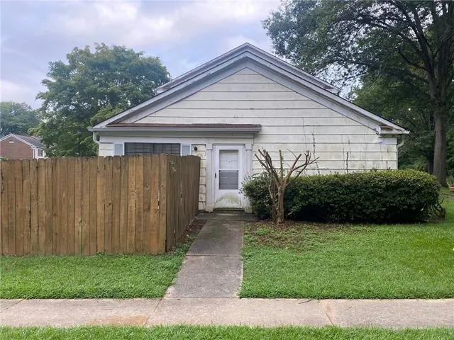 a view of a house with a yard plants and large tree