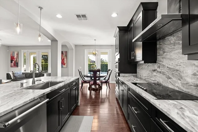 a kitchen with stainless steel appliances kitchen island granite countertop a table chairs sink refrigerator and microwave