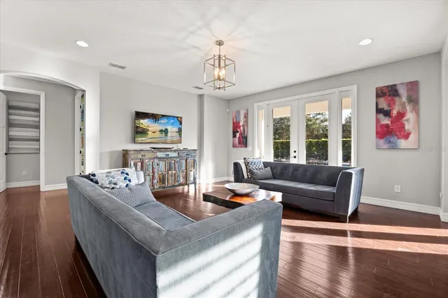 a living room with furniture kitchen view and a wooden floor