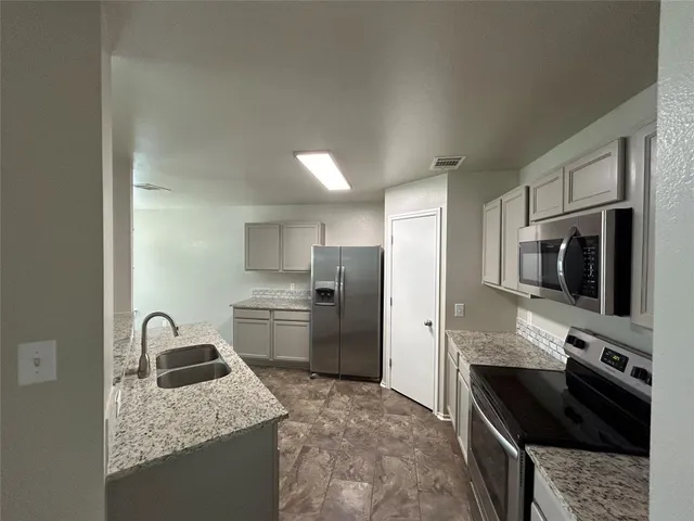 a kitchen with stainless steel appliances granite countertop a stove refrigerator and a sink