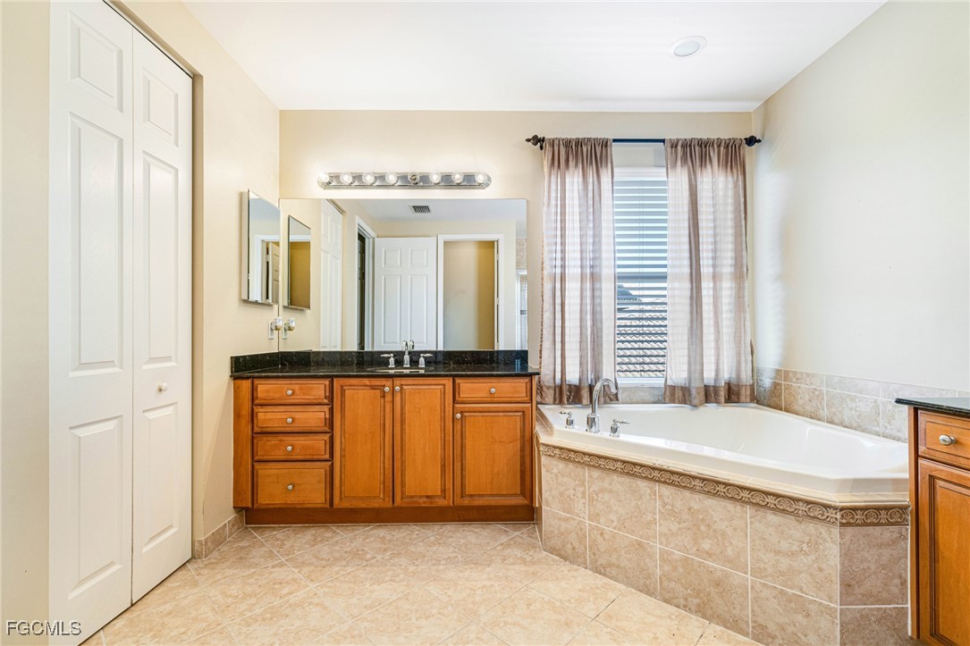 11196 Sand Pine Court Fort Myers, FL 33913 - Photo 17 of 49 a spacious bathroom with a tub a double vanity sink and mirror