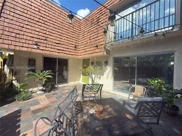a view of a patio with table and chairs potted plants and wooden fence