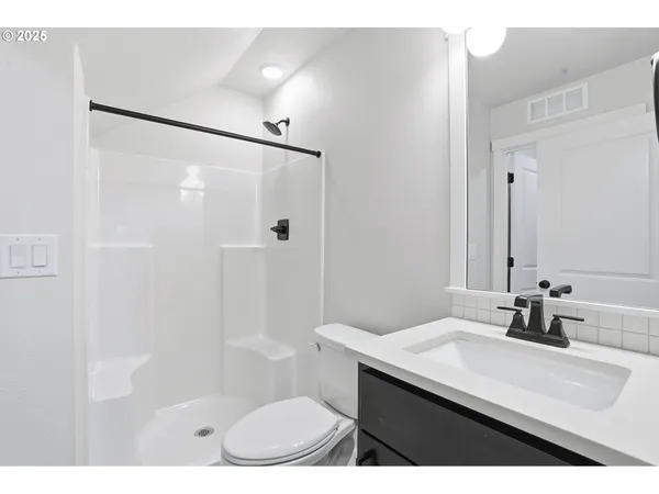 a bathroom with a sink a toilet a mirror and shower
