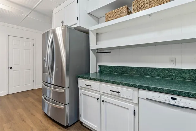 a kitchen with granite countertop a refrigerator and wooden floor