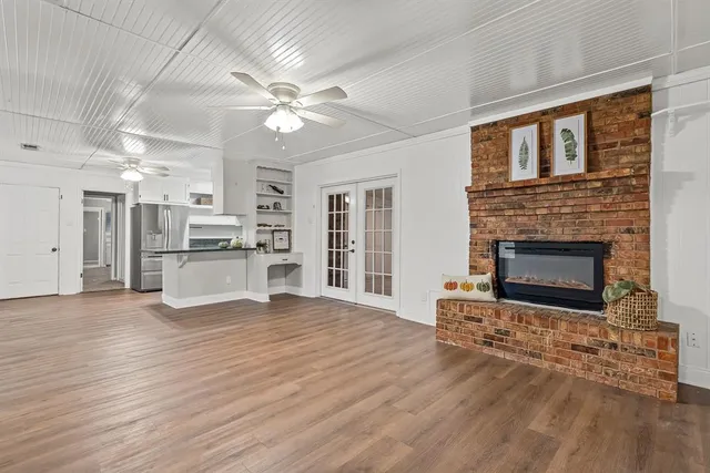 a view of a livingroom with a fireplace a ceiling fan and windows