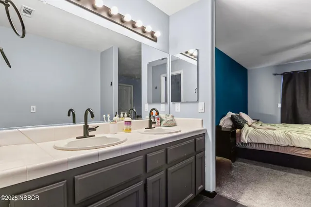 a en suite bathroom with a double vanity sink and a mirror