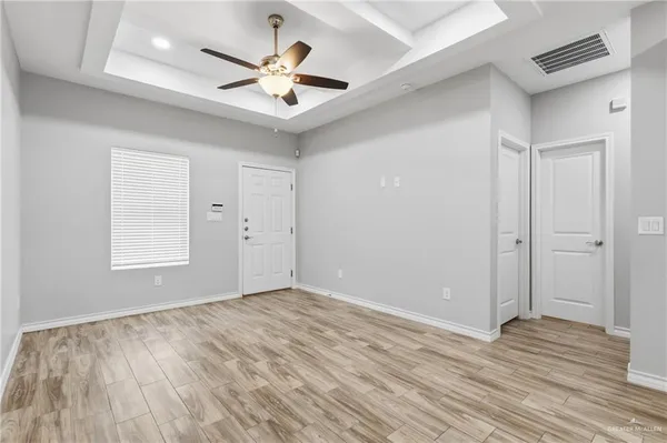 an empty room with wooden floor and ceiling fan