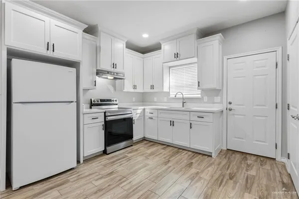 a kitchen with a refrigerator wooden floor a sink and cabinets