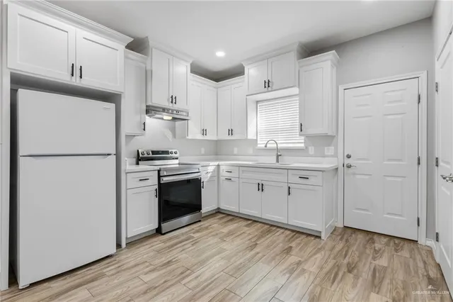 a kitchen with a refrigerator wooden floor a sink and cabinets