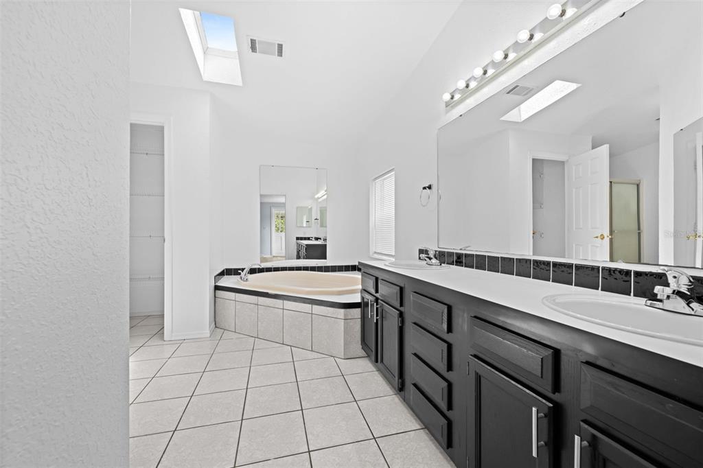 33320 Larkin Road Dade City, FL 33523 - Photo 32 of 60 a large bathroom with a double vanity sink a mirror and a bathtub