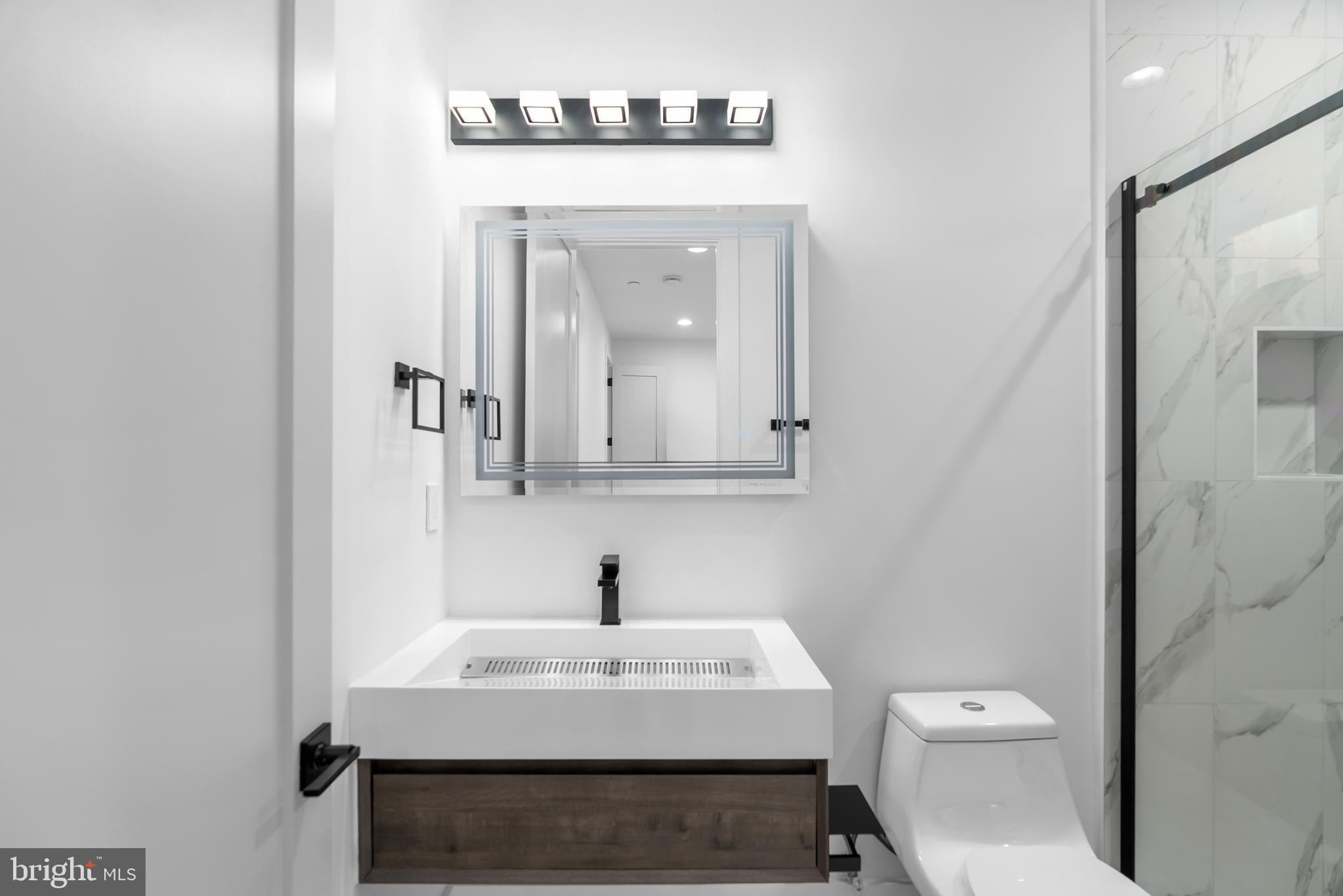 1140 Oates Street Northeast, Unit 102 Washington, DC 20002 - Photo 28 of 40 a bathroom with a sink a toilet and mirror