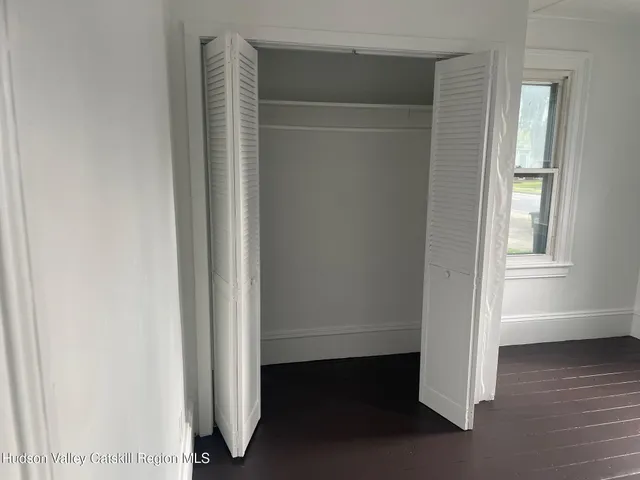 an empty room with wooden floor closet and windows