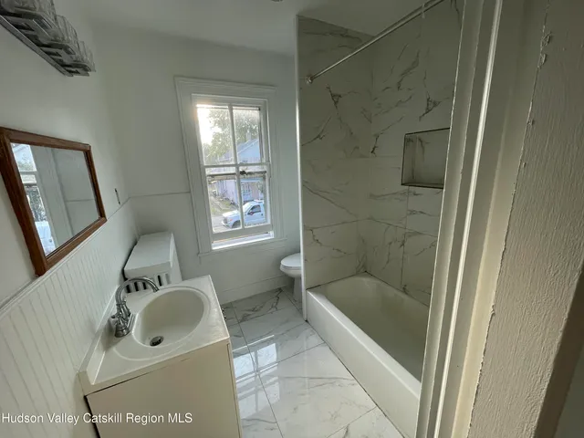 a bathroom with a tub sink toilet and mirror