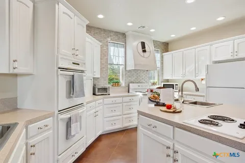 a kitchen with granite countertop white cabinets and white appliances