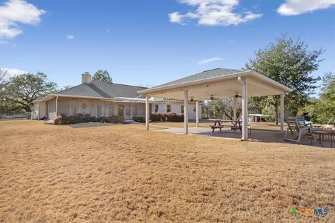 a backyard of a house with table and chairs under an umbrella