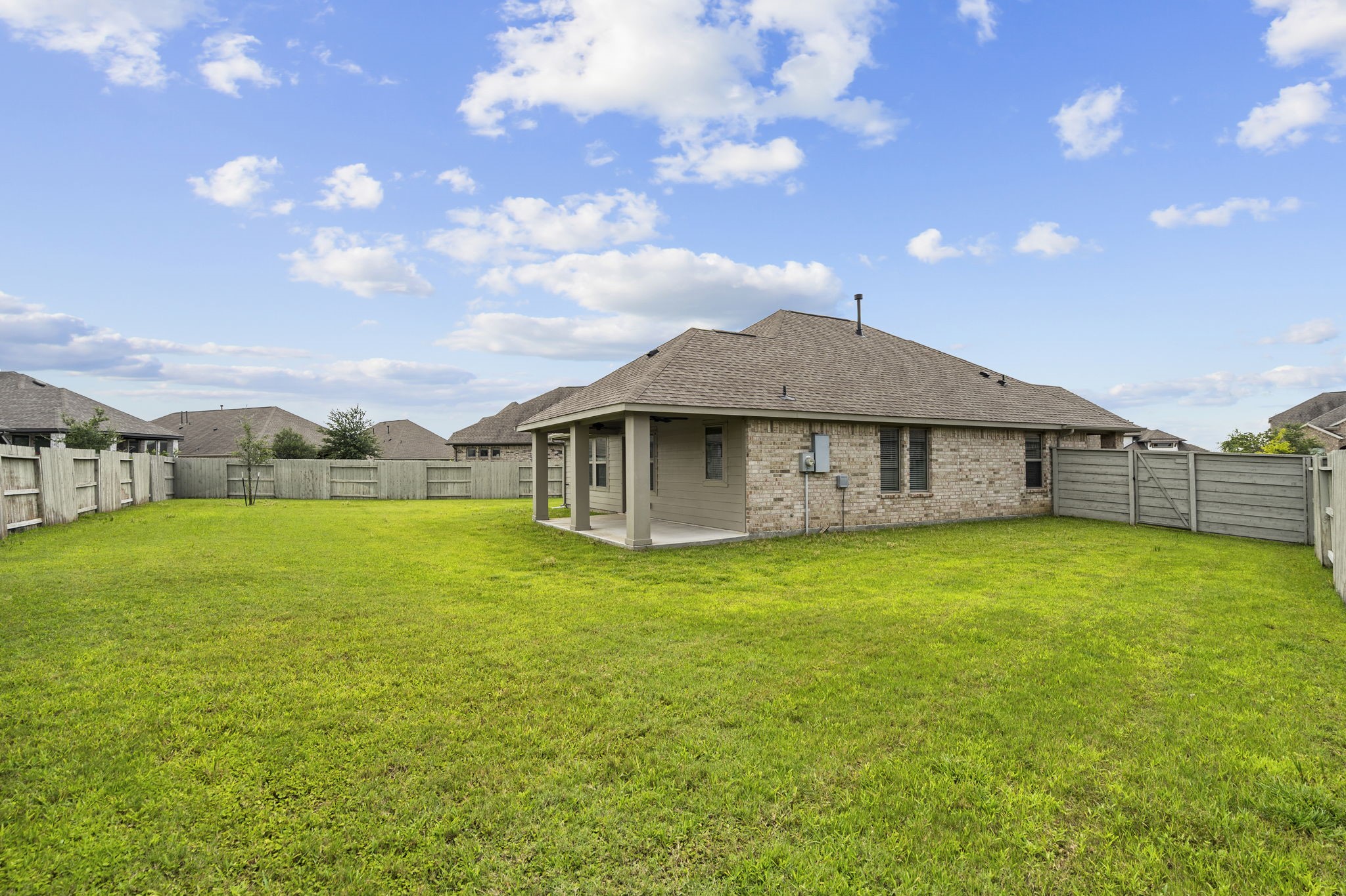 2011 Oak Leaf Court Manvel, TX 77578 - Photo 23 of 28 Spacious backyard with a well-maintained lawn, featuring a brick house with a covered patio, ideal for outdoor activities and relaxation.