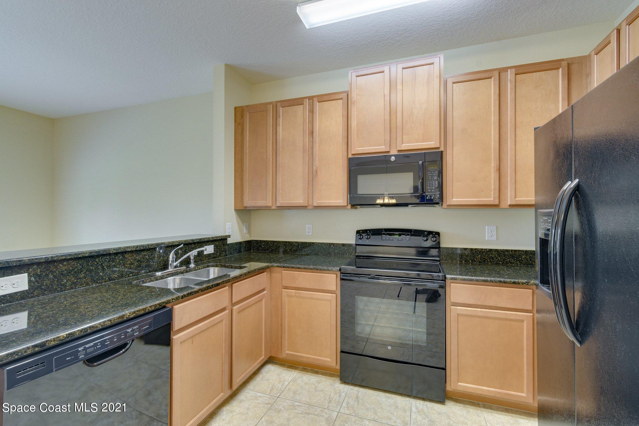 2780 Reston Street, Unit 102 Melbourne, FL 32935 - Photo 6 of 36 a kitchen with stainless steel appliances granite countertop a stove a refrigerator and a sink