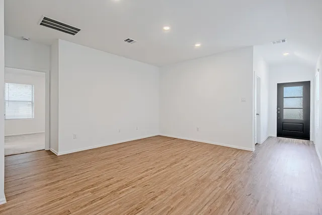 a view of an empty room with wooden floor and closet