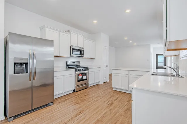 a kitchen with granite countertop a refrigerator stove and sink