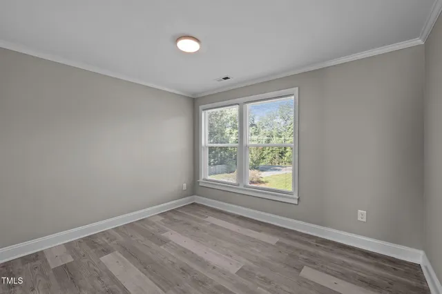 a view of an empty room with wooden floor and windows