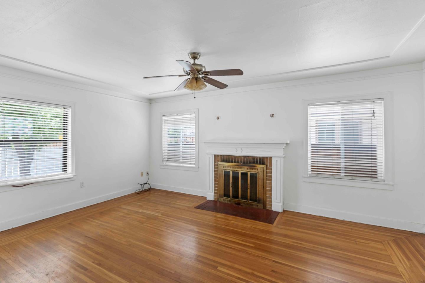 16735 Shannon Road Los Gatos, CA 95032 - Photo 3 of 19 an empty room with wooden floor fireplace and windows