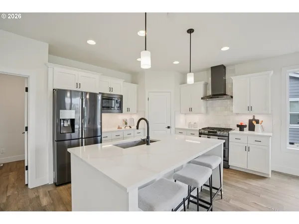a kitchen with stainless steel appliances kitchen island granite countertop a sink a stove a refrigerator and a dining table with wooden floor