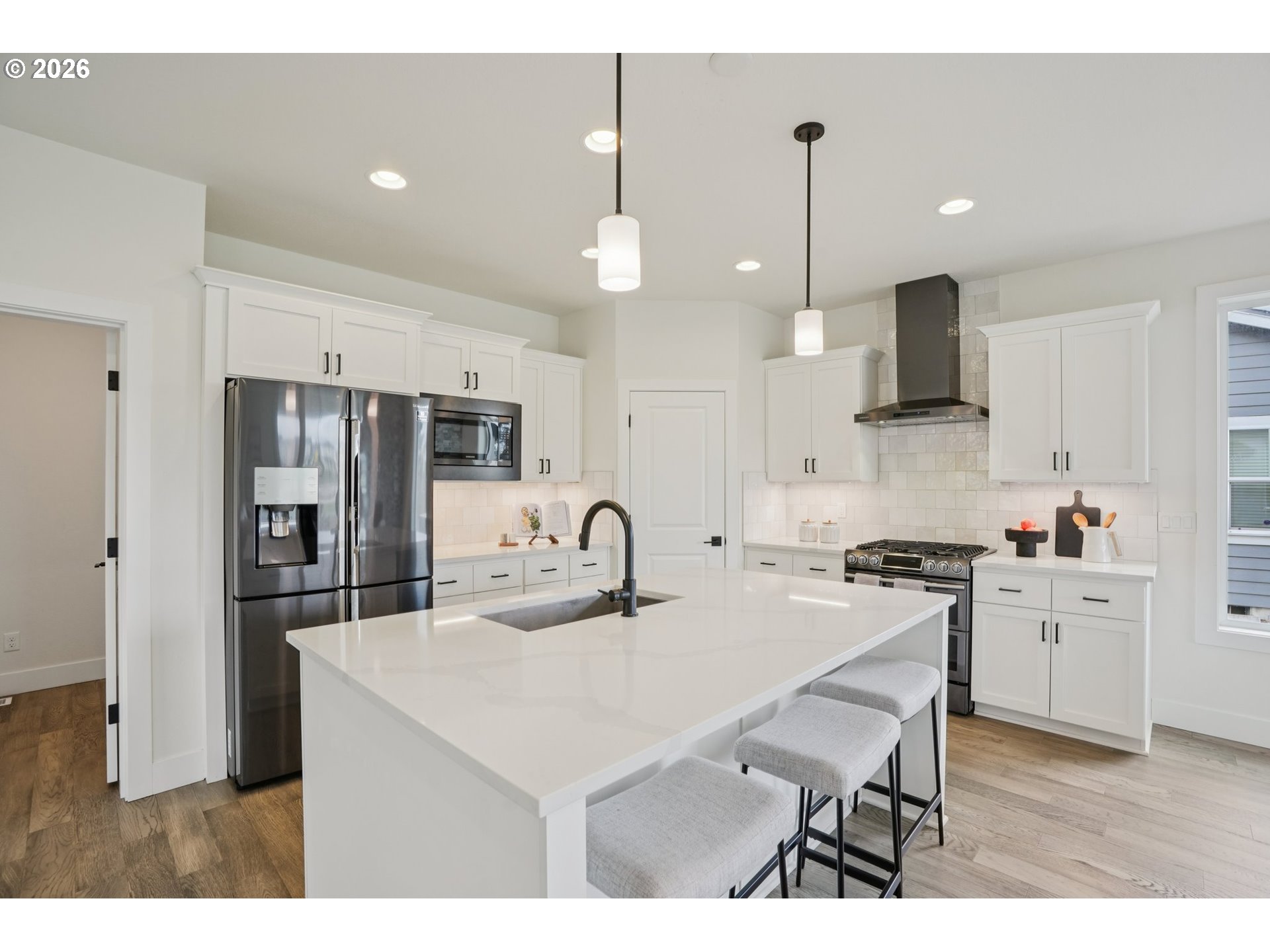3809 Southeast Reed Drive Hillsboro, OR 97123 - Photo 10 of 40 a kitchen with stainless steel appliances kitchen island granite countertop a sink a stove a refrigerator and a dining table with wooden floor