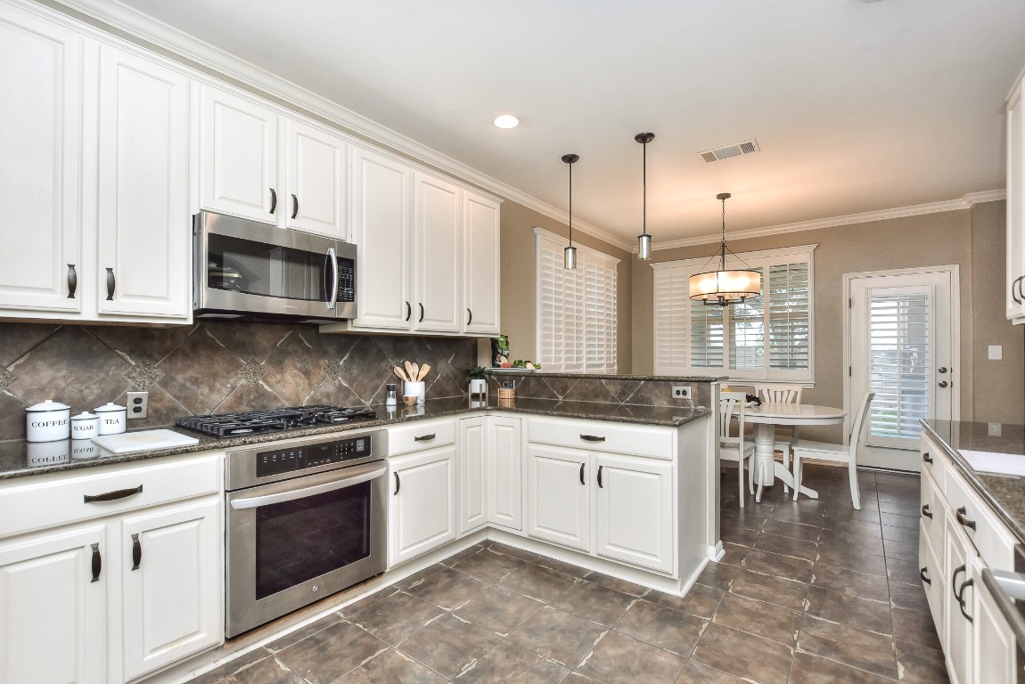 1108 Ritter Drive Cedar Park, TX 78613 - Photo 13 of 40 Charming kitchen features stainless appliances including gas cooktop, built-in oven and microwave, granite countertops, and pendant lighting.
