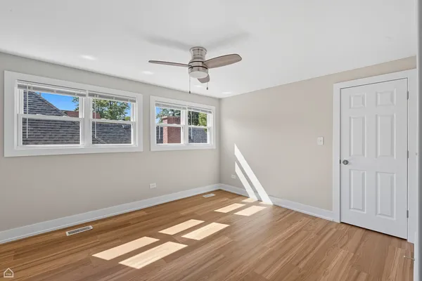 a view of empty room with wooden floor and fan