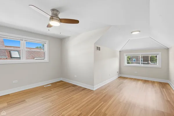 a view of empty room with wooden floor and fan
