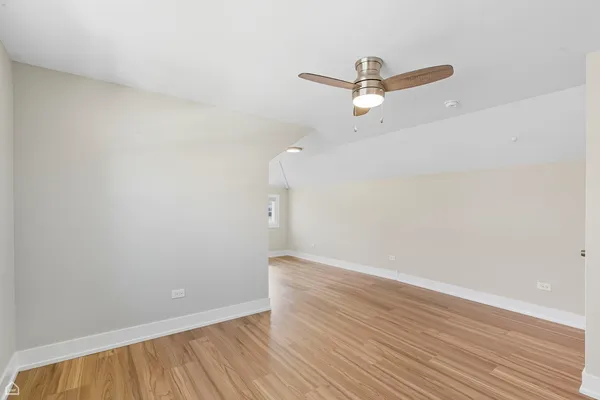 an empty room with wooden floor and ceiling fan