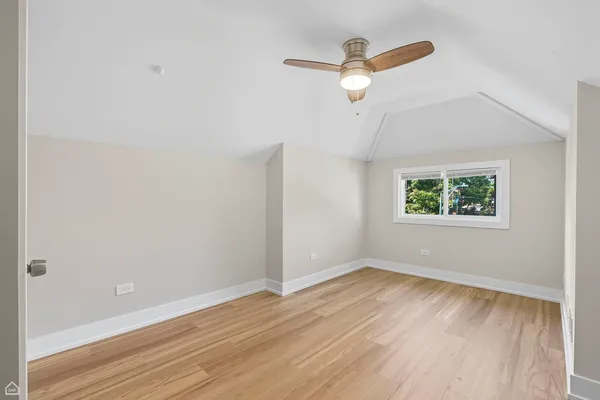 an empty room with wooden floor ceiling fan and window