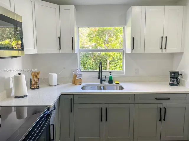 a kitchen with stainless steel appliances granite countertop white cabinets a sink and a window