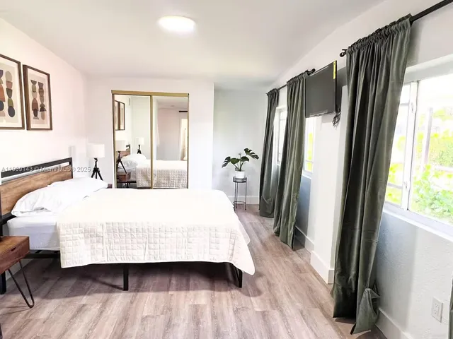 a bedroom with a bed and a large mirror next to a window