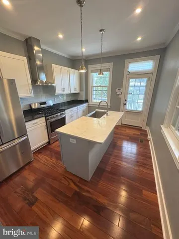 a large kitchen with stainless steel appliances granite countertop a sink a stove and a wooden floors