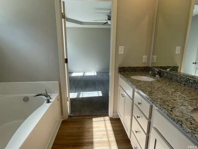 a spacious bathroom with a granite countertop tub sink and mirror