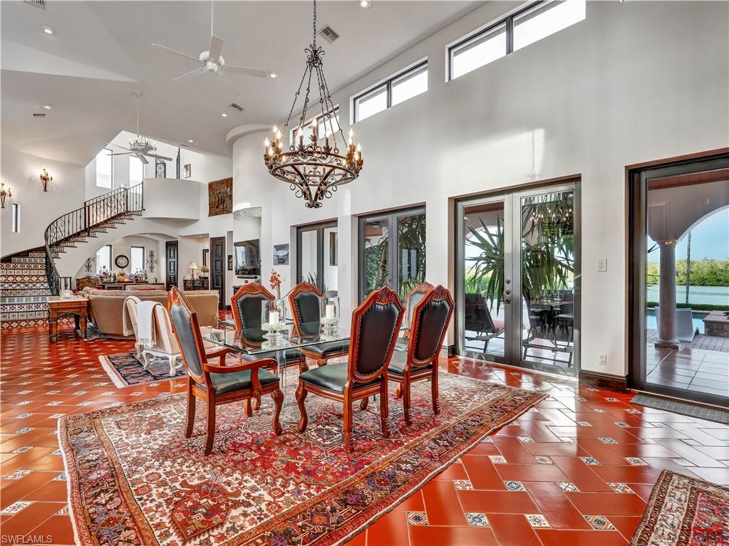 2535 Tarpon Road Naples, FL 34102 - Photo 11 of 50 Spacious living area featuring terra cotta tile flooring with decorative inserts, a grand chandelier, and a recessed ceiling dome