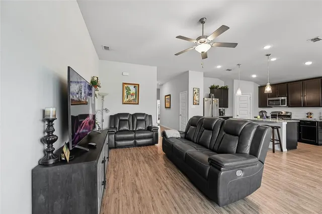 a living room with furniture kitchen view and a flat screen tv