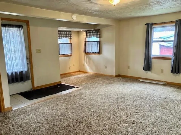 a view of an empty room with kitchen and wooden floor