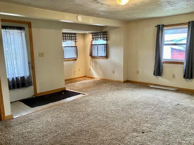 a view of an empty room with kitchen and wooden floor