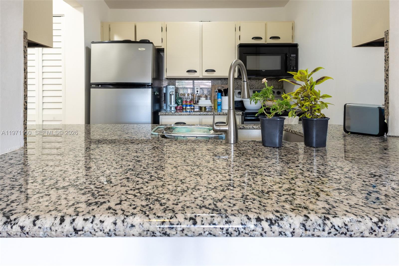 9430 Boca Cove Circle, Unit 210 Boca Raton, FL 33428 - Photo 11 of 24 a kitchen with a refrigerator a stove a counter space and a view of living room