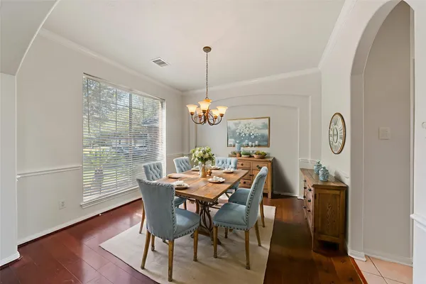 a view of a room with wooden floor chandeliers and kitchen view