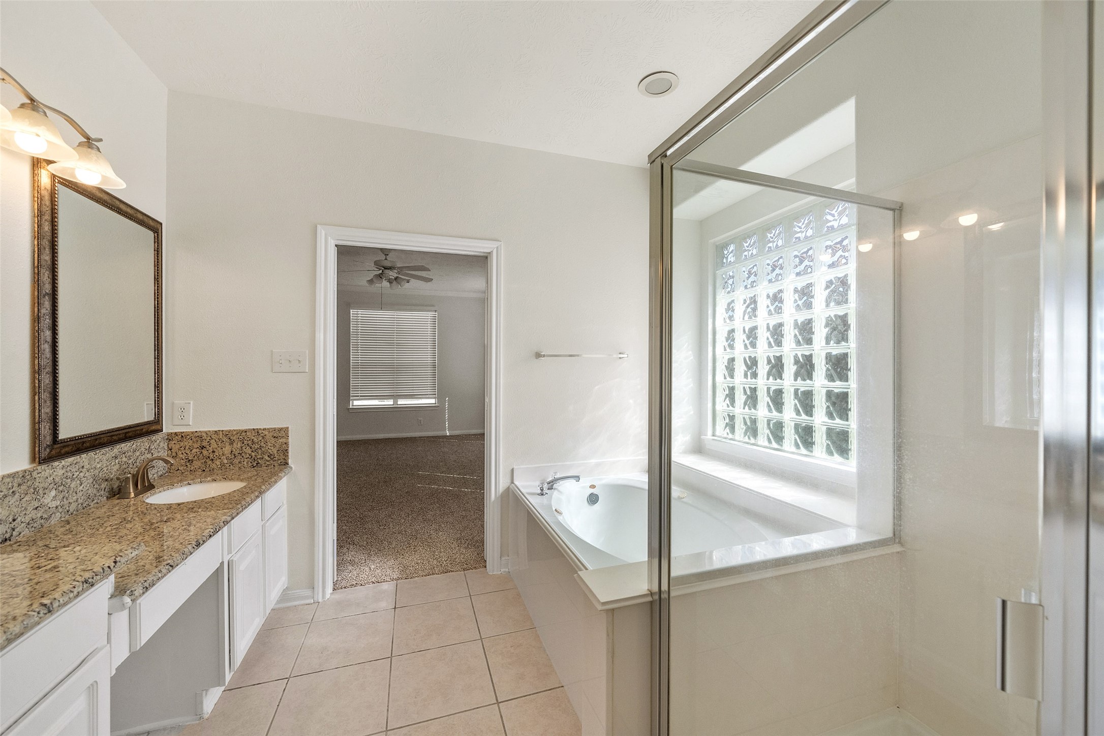 14213 Stone Bluff Lane Rosharon, TX 77583 - Photo 28 of 45 a bathroom with a granite countertop sink a mirror and a bathtub