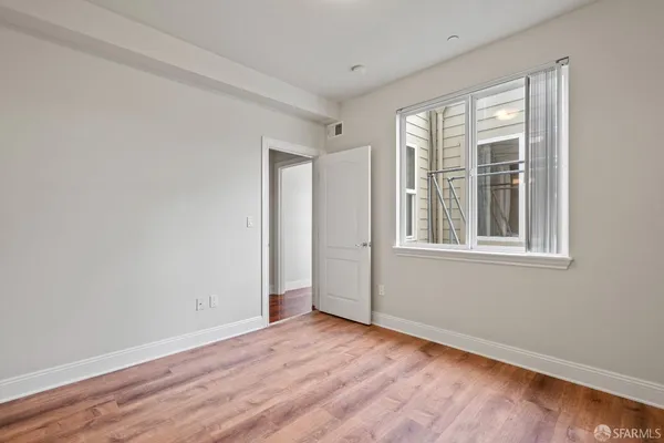 a view of an empty room with wooden floor and a window