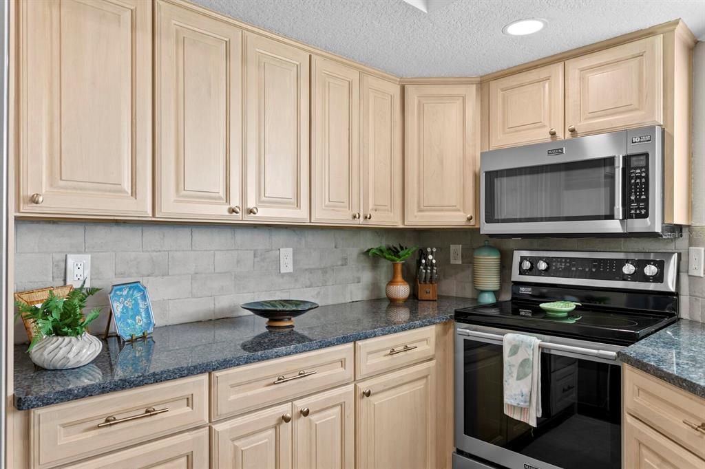 16332 Gulf Boulevard, Unit 3B Redington Beach, FL 33708 - Photo 20 of 93 a kitchen with stainless steel appliances granite countertop white cabinets sink and stove