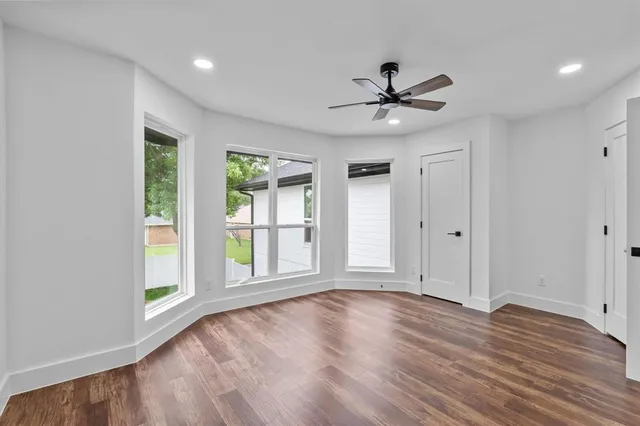 a view of an empty room with a window and wooden floor