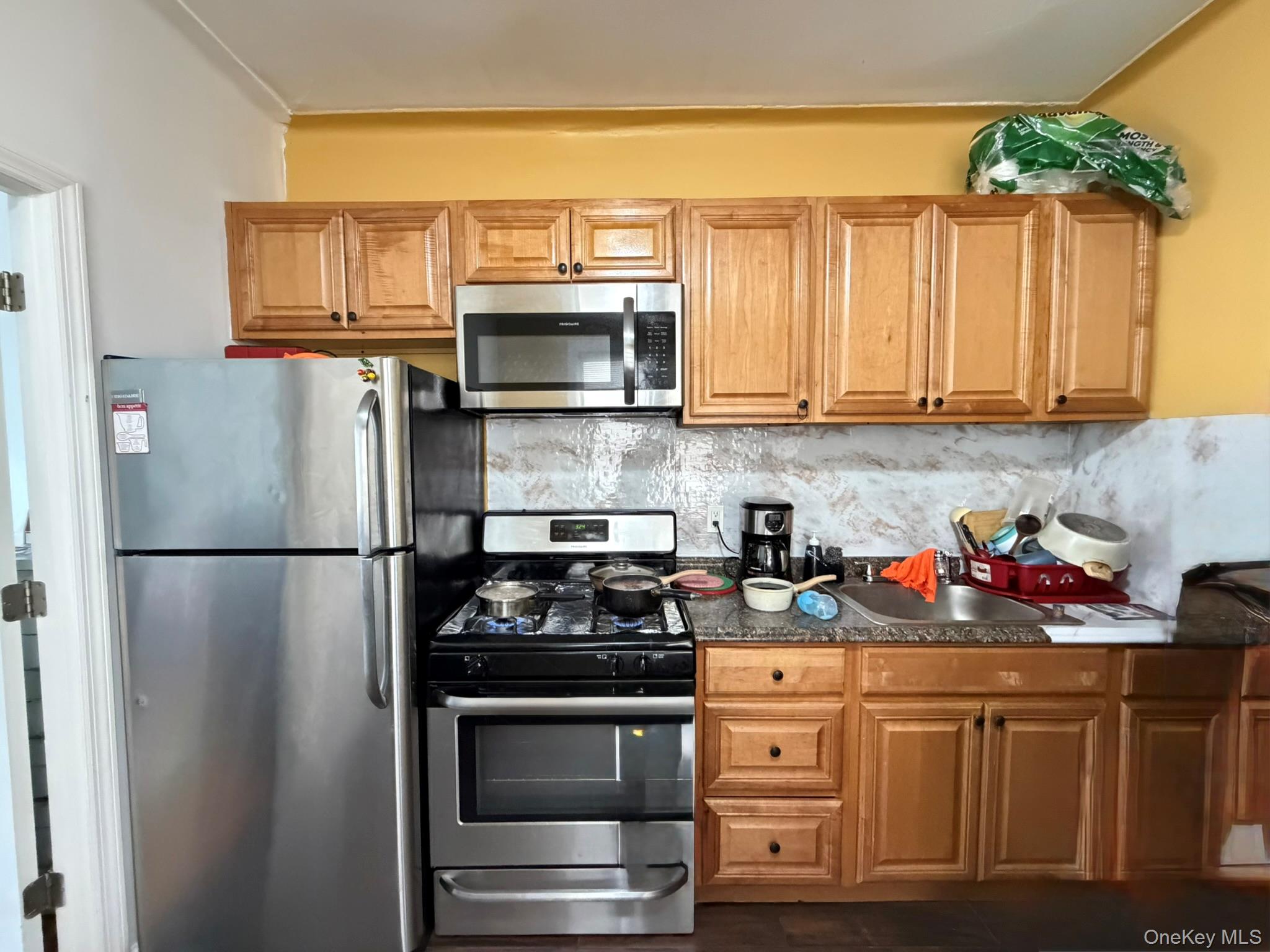 100-04 Spruce Street Queens, NY 11368 - Photo 4 of 12 a kitchen with stainless steel appliances a stove a refrigerator and cabinets