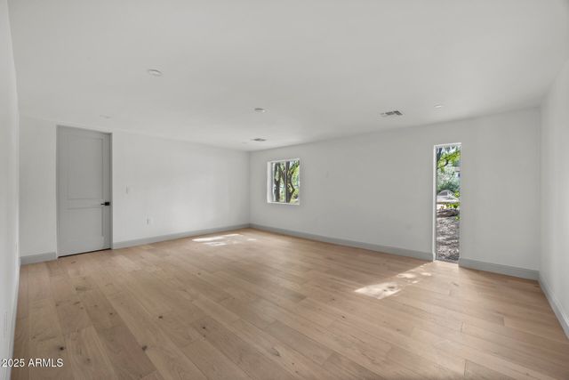 a view of an empty room with window and wooden floor