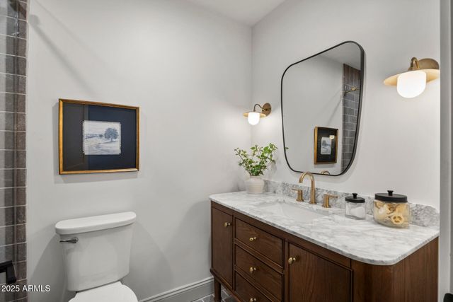 a bathroom with a granite countertop sink and a mirror with toilet